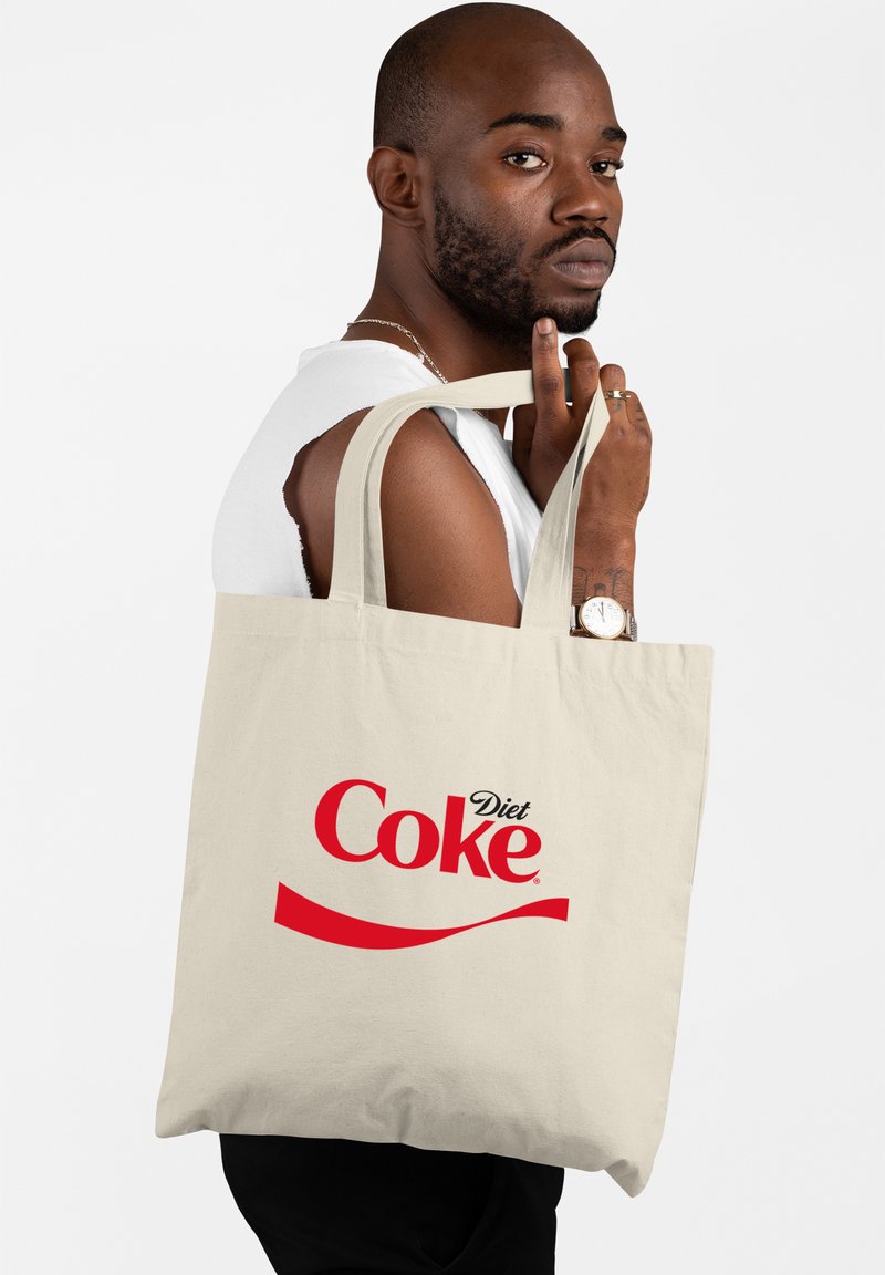 Beige katoenen tas met dikke handvatten, met een prominent rood "Diet Coke" logo en een gebogen rode accent aan de voorkant.