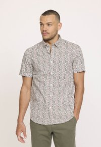 Chemise à manches courtes à boutons en tissu blanc avec un imprimé floral aux accents rouges et verts, dotée d'un col et d'une coupe décontractée.