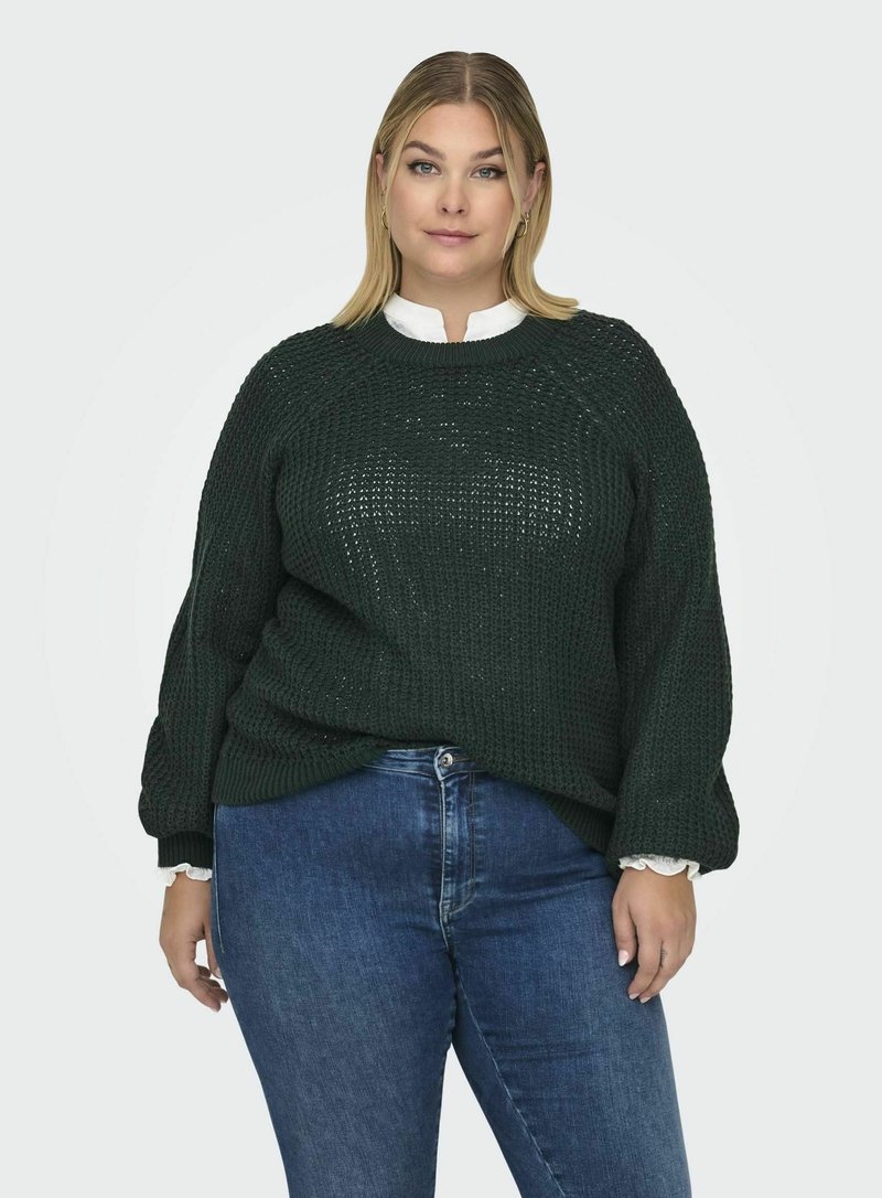 Pulover chunky de culoare verde închis, cu guler rotund, mâneci raglan și manșete cu dantelă, purtat peste o cămașă albă cu guler.