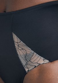 Black bikini bottom featuring a lace mesh panel on one side with a floral pattern. Soft texture and seamless design enhance comfort.