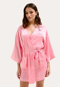 Robe en satin rose avec de larges manches kimono, une ceinture à nouer et deux poches avant ; présente un logo brodé sur la poitrine gauche.