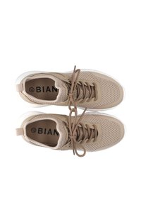 Beżowe sneakersy z siateczkową cholewką, okrągłym noskiem i płaską gumową podeszwą. Posiadają brązowe sznurówki i małe logo wewnątrz. Akcenty w białym kolorze na podeszwie.