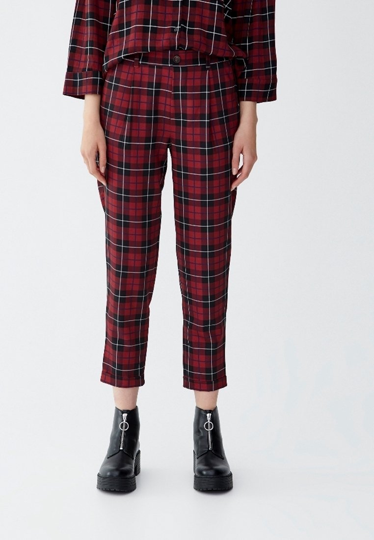 Pantalon à carreaux rouge et noir avec une coupe ajustée, une longueur raccourcie et une texture de tissu lisse. Assorti à des bottines noires avec des accents de zip.
