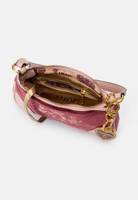 Borsa rosa e rosa chiaro realizzata in materiali scamosciati e in pelle, con hardware dorato, una tasca interna e un ciondolo a forma di cuore.