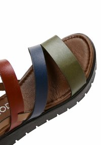 Sándal de cuero multicolor con tiras rojas, azules y verdes, plantilla acolchada marrón y suela de goma negra con plantilla antideslizante.