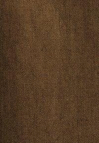 Gros plan d’un tissu tissé brun grossier avec un motif texturé de fils entrelacés créant une surface en forme de grille.
