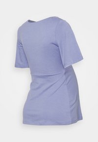 T-shirt lilás de manga curta, feita de tecido suave, com decote redondo e forma ligeiramente ajustada, apresentando detalhes de franzido nas laterais.