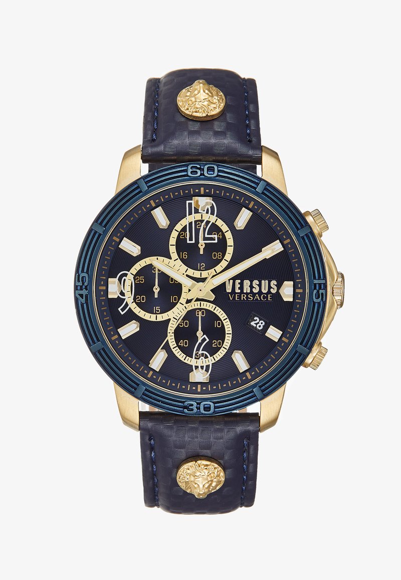 Reloj de acero inoxidable con acabado en tono dorado y correa de cuero texturizado azul marino, bisel azul y múltiples diales de cronógrafo. Presenta un acento en forma de cabeza de león.