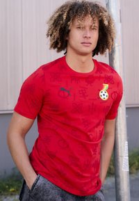 Rød kortærmet t-shirt lavet af blødt stof, med et lagdelt design med mønstre og et logo-patch, suppleret med en rund halsudskæring.