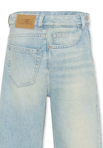 Jean en denim bleu clair délavé avec des poches arrière, des passants pour ceinture, et une étiquette en cuir beige sur la ceinture.