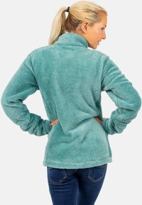 Pullover in pile di colore teal chiaro, con colletto alto, maniche lunghe e una finitura morbida e texturizzata. Vestibilità sagomata con fondo orlato.