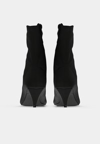 Μαύρα μποτάκια αστραγάλου με κομψό σχέδιο, κατασκευασμένα από λείο υλικό, με κωνικό τακούνι και φερμουάρ στο πίσω μέρος.