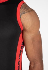 Ärmelloses schwarzes Sportoberteil mit roten Akzenten und einem Logo. Verfügt über ein figurnahes Design, eine glatte Textur und sichtbare Nahtdetails an den Ärmeln.