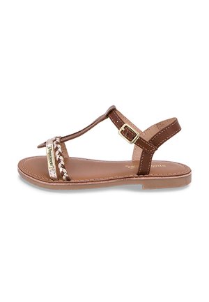 Brown leather sandals with a woven strap, adjustable ankle buckle, flat sole, and minimalistic design. Accents include a metallic logo detail.
