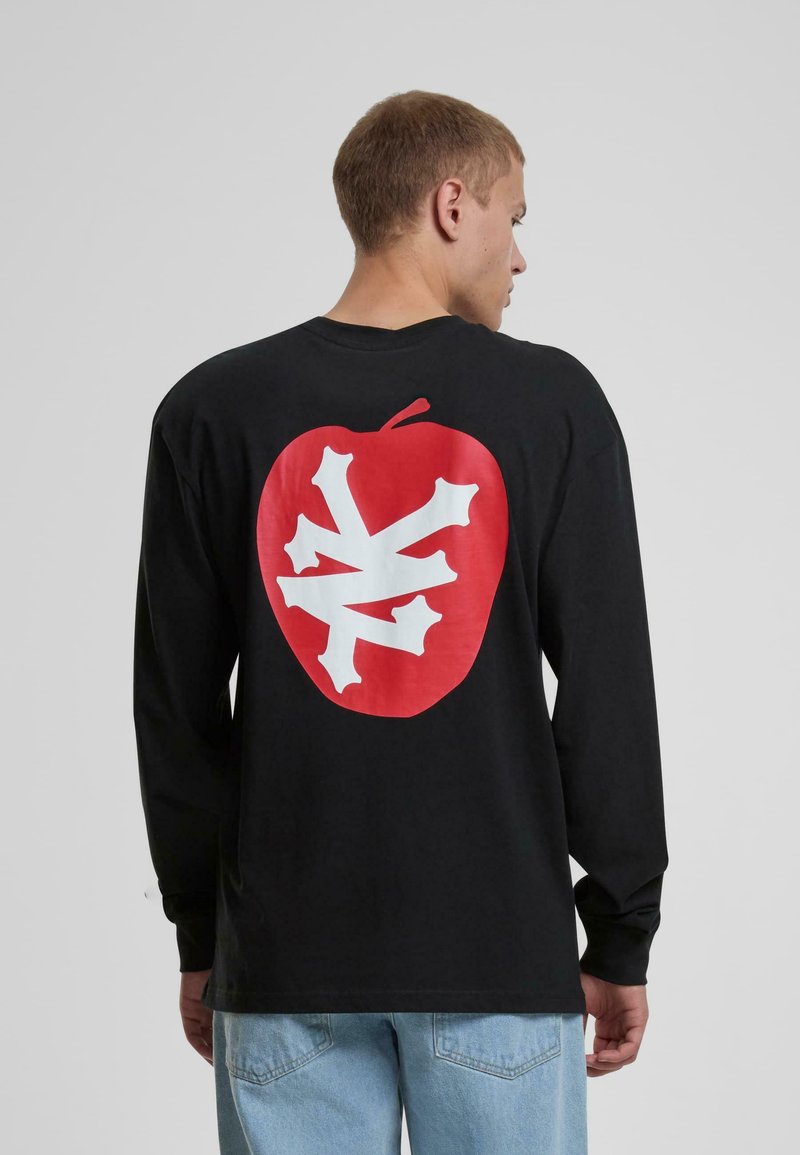 Schwarzes Langarm-T-Shirt mit einem großen roten Apfel-Graphic und einem weißen Schneeflocken-Design auf dem Rücken. Aus Baumwolle, lockere Passform.