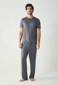 Šedý pyžamový set vyrobený z měkké, lehké tkaniny. Tričko s krátkým rukávem a dlouhé kalhoty s elastickým pasem. Jednoduchý, elegantní design.