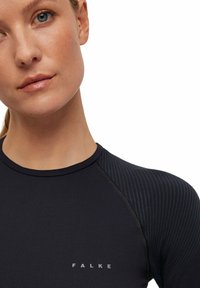 Czarna sportowa bluzka z długim rękawem, charakteryzująca się prążkowaną teksturą na ramionach, okrągłym dekoltem oraz logo z przodu w jaśniejszym odcieniu.