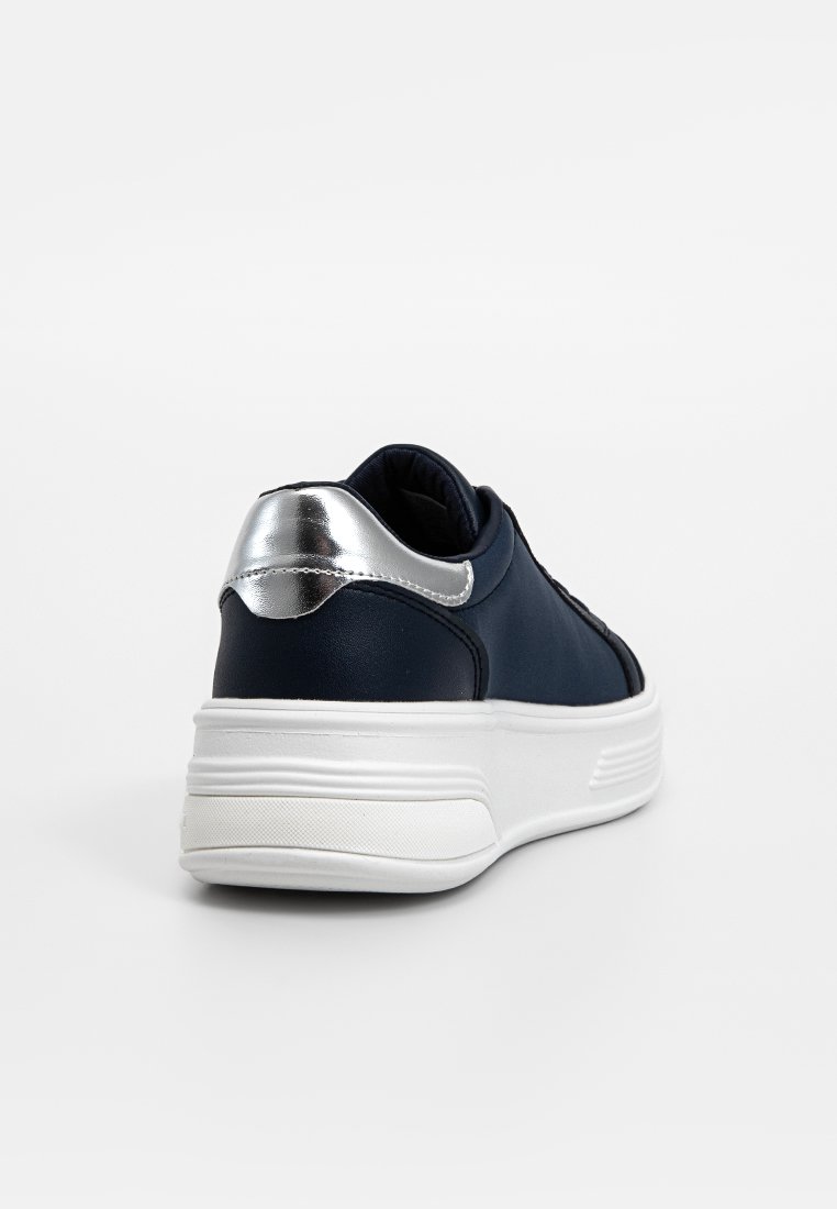 Sneaker blu navy con texture liscia, suola bianca e dettaglio argentato metallico sul tallone. Silhouette elegante con collarino imbottito.