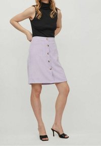 Lila corduroy rok met verticale ribbels, voorzien van zes houten knopen aan de voorkant en een zoom die net boven de knie valt.