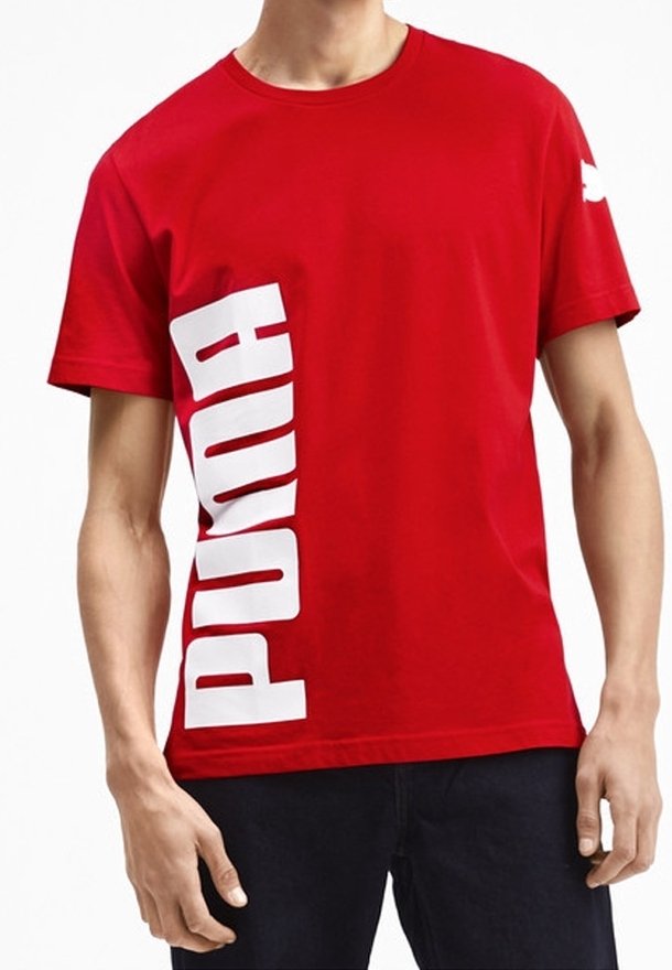T-shirt en coton rouge avec un grand logo "PUMA" blanc imprimé verticalement sur le côté gauche. Manches courtes et col rond.