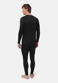 Black long-sleeve thermal top and fitted leggings. Ribbed texture, slim fit, and crew neckline. Seamless design with minimal branding.