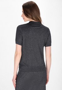 Maglione a maniche corte, grigio scuro, con un collo alto e un materiale testurizzato e scintillante. Orlo e polsini a coste, silhouette aderente.