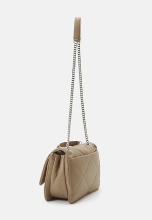 Kleine beige gesteppte Ledertasche mit silberner Kettenriemen und Leder-Schulterpolster, dargestellt hängend vor einfachem Hintergrund.