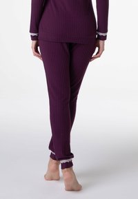 Set di abbigliamento da soggiorno viola a costine composto da top con maniche lunghe e pantaloni aderenti. I pantaloni presentano un bordo in pizzo alle estremità e una silhouette rilassata.