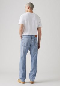 Lyseblå denim jeans med en avslappet passform, med et lærpatch på midjen, baklommer og en rett ben-design.