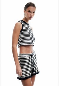 Conjunto de top corto y pantalones cortos de punto a rayas en blanco y negro, con escote acanalado, cintura con cordón y acentos de dobladillo con volantes.