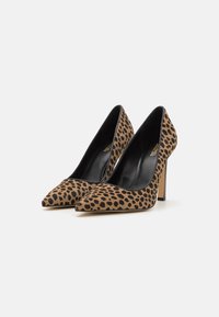 Escarpins à imprimé léopard, bout pointu, intérieur noir, texture douce semblable au daim, talon aiguille haut, combinaison de couleurs beige et noir.