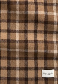 Bruin geruit stof met donkerbruine, lichtbruine en witte lijnen. Zachte textuur met een label dat "Marc O'Polo" leest.