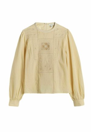 Bēša, garām piedurknēm blūze ar apaļu apkakli, rotāta ar smalku ziedu izšuvumu un plīsētām detaļām priekšpusē un uz pūderveida piedurknēm.