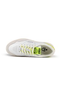 Zapatilla blanca con parte superior de cuero, puntera perforada y cordones amarillos vibrantes. Presenta una sutil entresuela texturizada y un detalle del logo en la lengüeta.