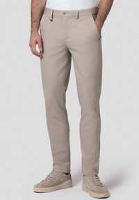 Beżowe chinosy wykonane z miękkiej tkaniny, w wąskim kroju, z ukośnymi kieszeniami i pojedynczym zapięciem na guzik, z subtelnymi detalami szycia.