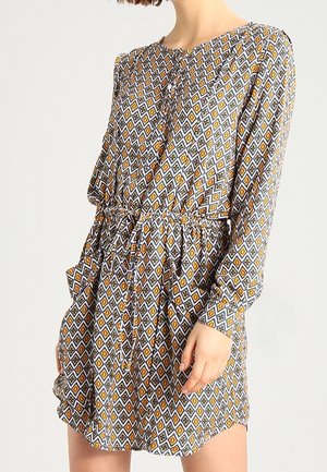 Robe à motifs avec un design géométrique en orange, gris et blanc, manches longues, encolure ronde et taille élastiquée.