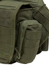 Olivgrön taktikväska med slitstark texturerad tyg, flera fickor och webbing för fästen. Fodrad huvudfack som är åtkomligt.