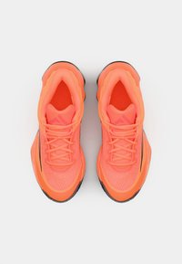 Bright orange athletic shoes with a textured mesh upper, rounded shape, and black rubber soles. Laces and cushioned collar for support.
