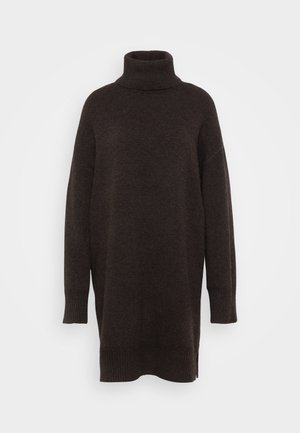 Brūns turtlenecks džemperis ar brīvu piegriezumu, izgatavots no maiga adījuma auduma. Iezīmes ir garas piedurknes un ribotās akcenti pie aprocēm un apakšmalas.