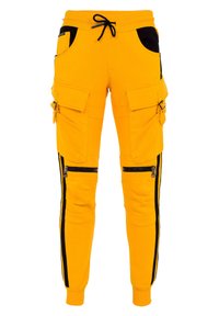 Gelbe Cargo-Hosen aus Baumwolle, mit schwarzen Akzenten, mehreren Taschen und Reißverschlüssen entlang der Seite.