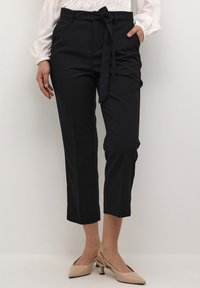 Svarta skräddarsydda byxor med knytbälte, kapad längd och en slät textur. Matchade med beige klackar med spetsig tå och unik klackdesign.