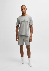 Gray cotton t-shirt and shorts set featuring a logo in the center, clean design, short sleeves, and a relaxed fit. White ankle socks worn.