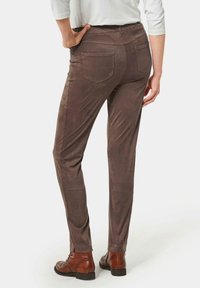 Bruine faux suede broeken met een slim fit, twee achterzakken en een gladde textuur, gecombineerd met bruine veterschoenen.