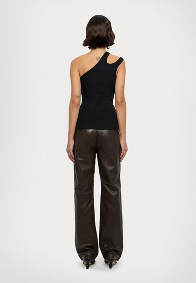 Top noir asymétrique en tissu ajusté avec un détail découpé sur l'épaule. Associé à un pantalon en cuir brun brillant, ample.