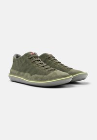 Grüne Netz-Sneaker mit Wildlederakzenten, flachen Schnürsenkeln, einem gepolsterten Knöchel und einer hellgrauen Gummisohle mit gelbem Rand.
