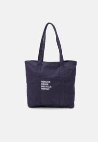 Granatowa torba z płótna z podwójnymi uchwytami, przednią kieszenią i białym napisem: "REDUCE REUSE RECYCLE REPEAT." Gładki, wytrzymały materiał.