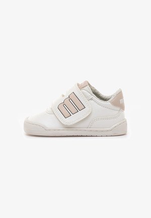 Zapatilla blanca para niño pequeño con detalles beige y una gran "m" en la tira de velcro para un fácil ajuste sobre suela de goma plana.
