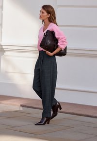 Lyserød ribbet sweater, højtaljede ternede bukser i mørkegrå, brun lædertaske og brune spidse hæle.