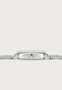 Montre en métal argenté avec un boîtier rectangulaire, surface lisse et bracelet gris texturé. Dispose d'une couronne sur le côté pour les réglages.