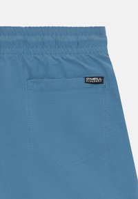 Šviesiai mėlyni maudymosi šortai su elastine juosta, turintys užpakalinę kišenę ir O'Neill Hyperdry etiketę. Lygus audinys, minimalus siuvimo detalės.